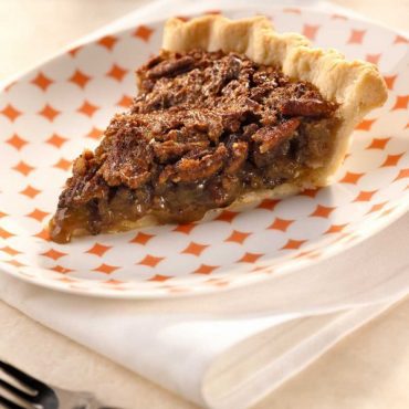 Chocolate Bourbon Pecan Pie on a decorative plate and white towel.