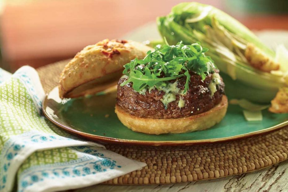 Wild Mushroom and Blue Cheese Stuffed Burger on a green plate placed on a table with a towel and woven place mat.