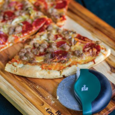 Pizza wheel and pizza on cutting board